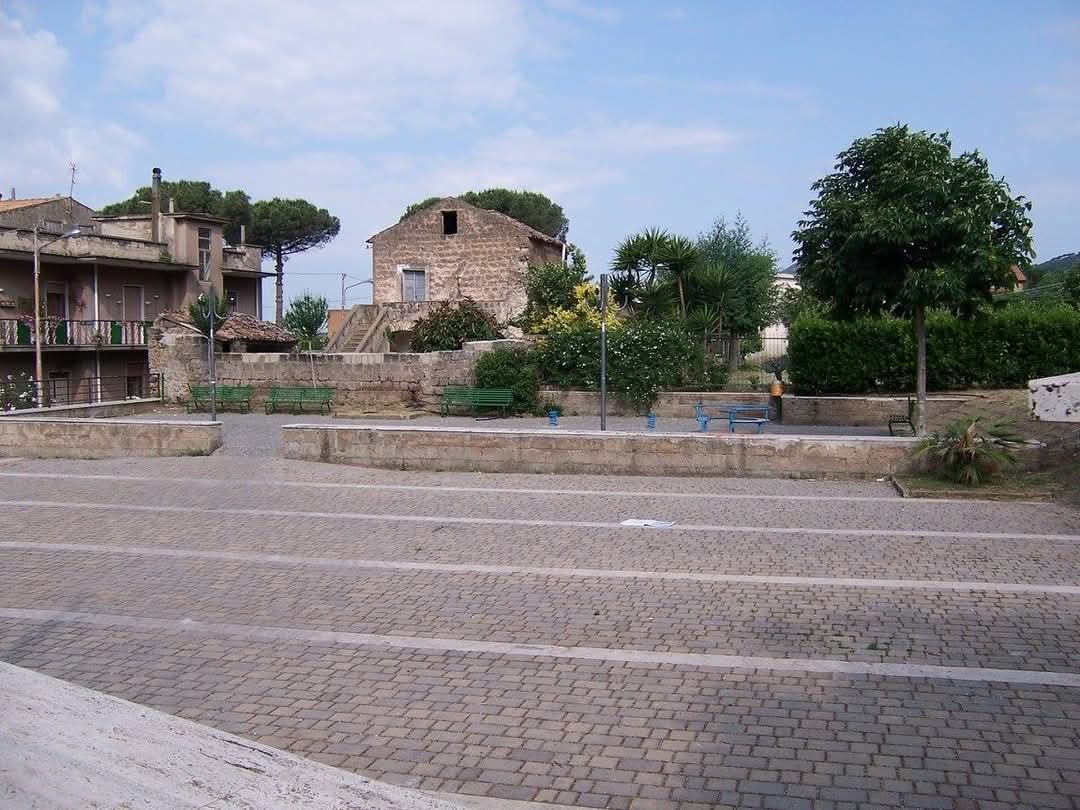 Una piazzetta del borgo con le panchine e le case in pietra sullo sfondo.
