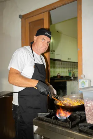 Un cuoco che cucina in padella sulla fiamma.